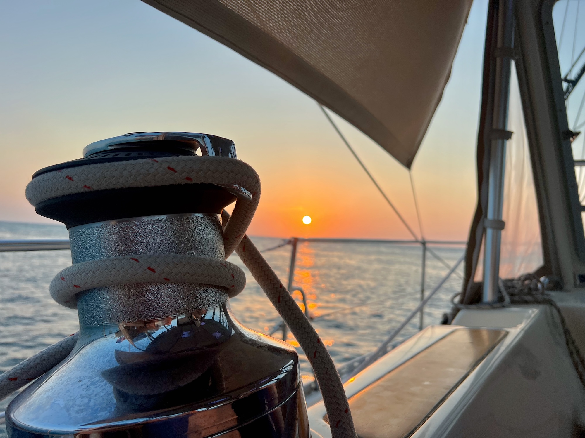 photo of a sunset from the view of a cockpit with a large winch in the foreground with a line wrapped around it